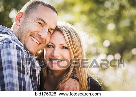 Stock Photo - Smiling couple hugging outdoors. Fotosearch