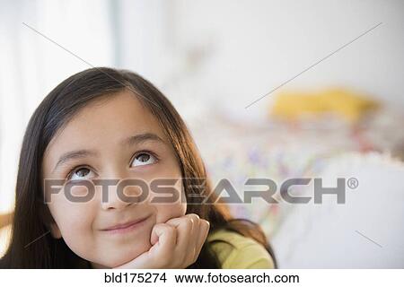 Picture - Smiling girl daydreaming with hand on chin. Fotosearch