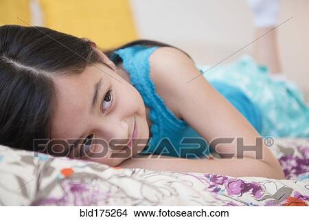 Picture - Smiling girl laying on bed. Fotosearch