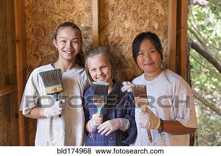 Stock Photo - Smiling girls painting house. Fotosearch