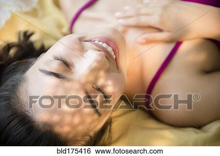 Stock Photograph - Smiling Hispanic woman laying down. Fotosearch