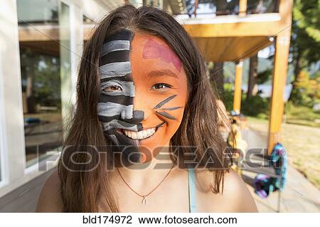 Stock Image - Smiling mixed race girl wearing face paint. Fotosearch