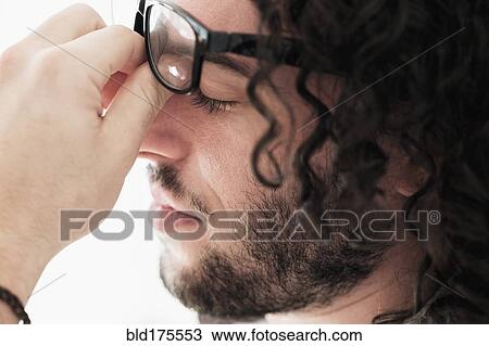 Stock Image - Stressed Caucasian man rubbing his eyes. Fotosearch