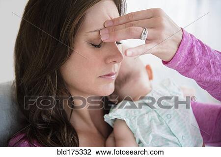 Stock Image - Stressed mother pinching her forehead. Fotosearch