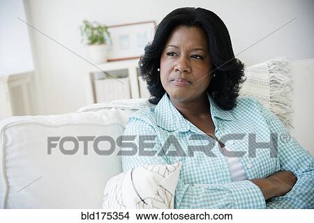 Picture - Unhappy Black woman sitting on sofa. Fotosearch