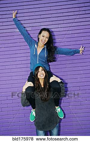 Stock Photo - Woman carrying friend on shoulders. Fotosearch
