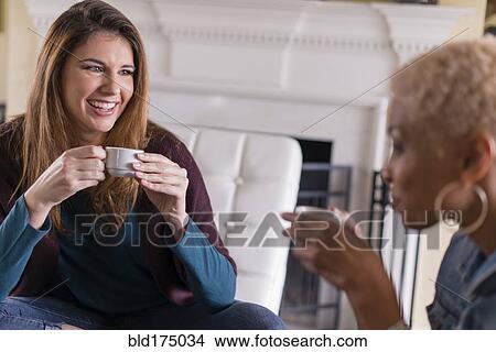 Picture - Women drinking coffee in living room. Fotosearch