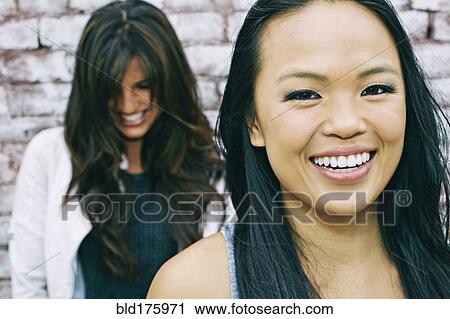 Women smiling at brick wall View Large Photo Image Stock Image - Women smiling at brick wall. Fotosearch