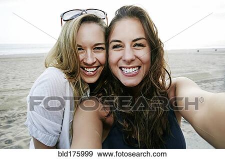 Stock Photo - Women taking selfie on beach. Fotosearch