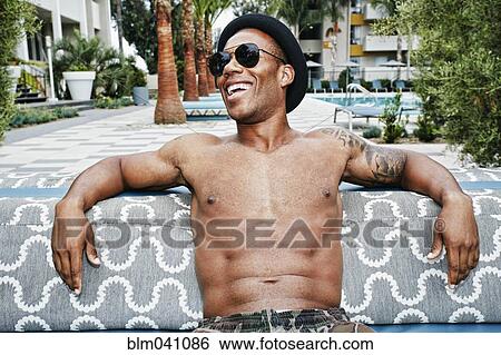 Stock Photograph - African American man sitting outdoors. Fotosearch