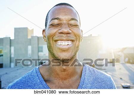 Stock Image - African American man smiling outdoors. Fotosearch