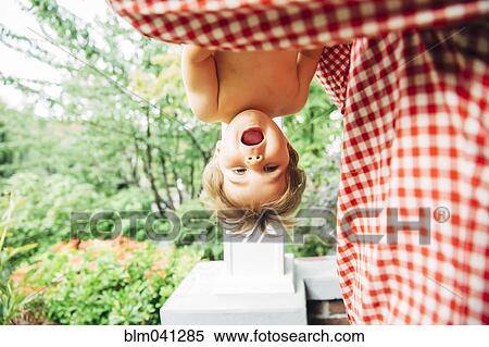 Stock Photography - Baby boy hanging upside down outdoors. Fotosearch