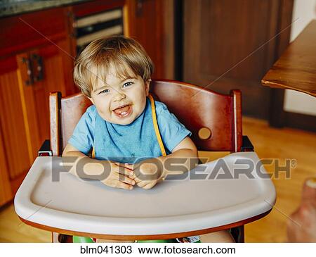 Stock Image - Baby boy laughing in high chair. Fotosearch