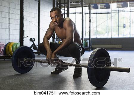 Black athlete crouching with weight in gym View Large Photo Image Stock Image - Black athlete crouching with weight in gym. Fotosearch