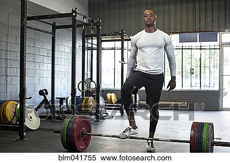 Stock Photography - Black athlete standing at barbell in gym. Fotosearch