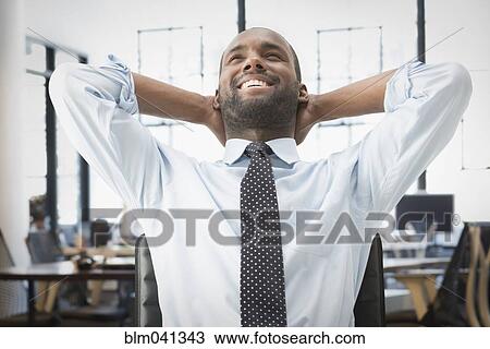 Black businessman stretching in office View Large Photo Image Stock Image - Black businessman stretching in office. Fotosearch