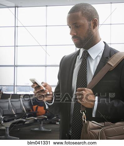 Black businessman using cell phone in airport View Large Photo Image Stock Image - Black businessman using cell phone in airport. Fotosearch