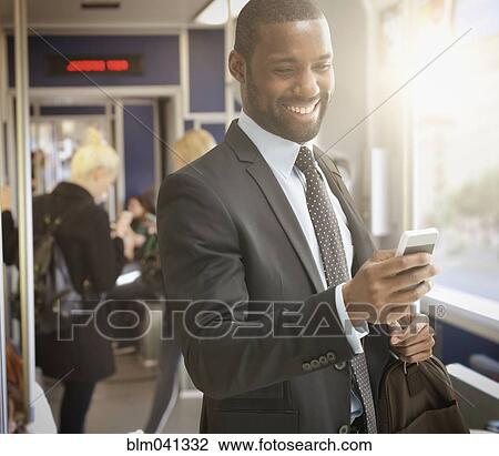 Stock Image - Black businessman using cell phone in subway. Fotosearch