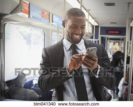 Stock Image - Black businessman using cell phone on subway. Fotosearch