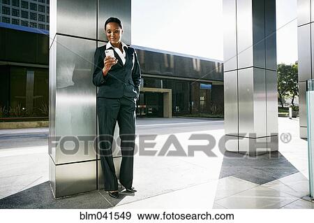 Stock Photo - Black businesswoman using cell phone outdoors. Fotosearch