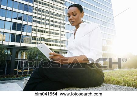 Picture - Black businesswoman using digital tablet outdoors. Fotosearch