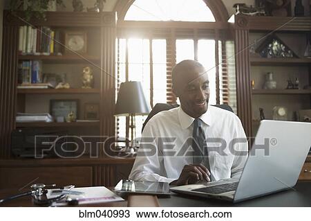 Stock Image - Black doctor using laptop in office. Fotosearch