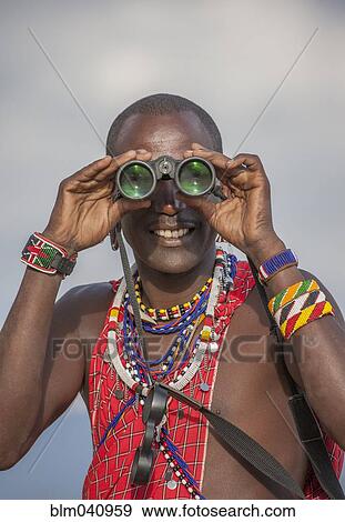 Stock Photo - Black man in traditional clothing using binoculars. Fotosearch