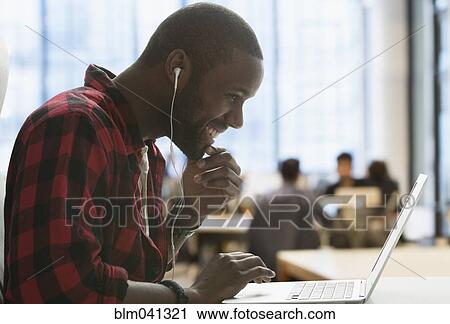Black man listening to earbuds in laptop View Large Photo Image Stock Image - Black man listening to earbuds in laptop. Fotosearch