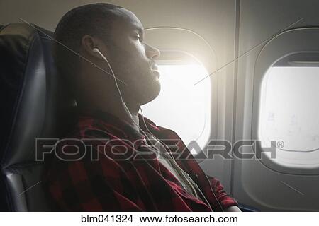 Black man listening to earbuds on airplane View Large Photo Image Picture - Black man listening to earbuds on airplane. Fotosearch