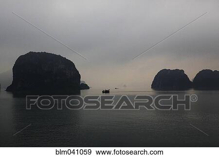 Stock Photo - Boat sailing near rock formations in Ha Long Bay, Quang Ninh Province, Vietnam. Fotosearch