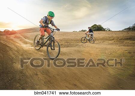 Stock Image - Boy riding dirt bikes on track. Fotosearch