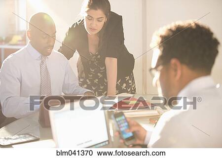 Stock Image - Business people talking in office meeting. Fotosearch
