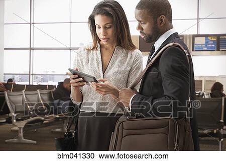 Stock Image - Business people using digital tablet in airport. Fotosearch