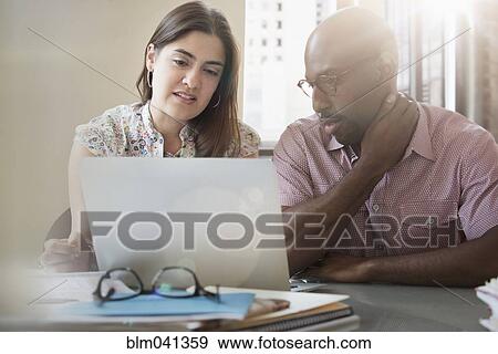Stock Photo - Business people using laptop in office. Fotosearch