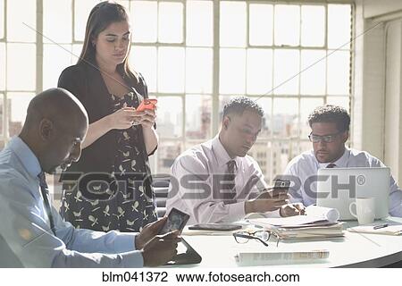 Stock Image - Business people using technology in office meeting. Fotosearch