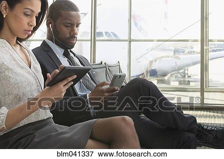 Stock Photo - Business people using technology in airport. Fotosearch