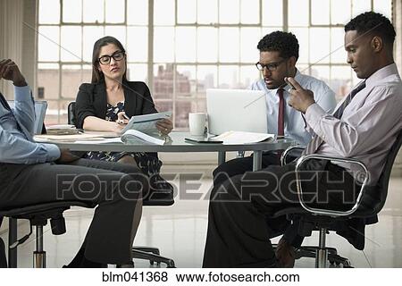 Stock Photo - Business people using technology in office meeting. Fotosearch