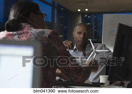 Stock Image - Business people working late in office. Fotosearch