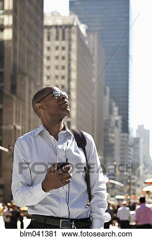 Stock Image - Businessman admiring high rise buildings in cityscape. Fotosearch