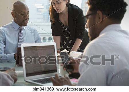 Stock Photo - Businessman multitasking in office meeting. Fotosearch