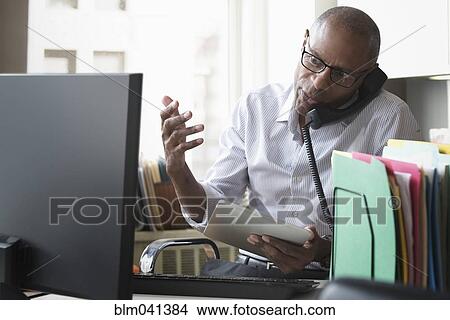 Picture - Businessman talking on phone in office. Fotosearch