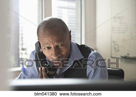 Stock Image - Businessman talking on phone in office. Fotosearch