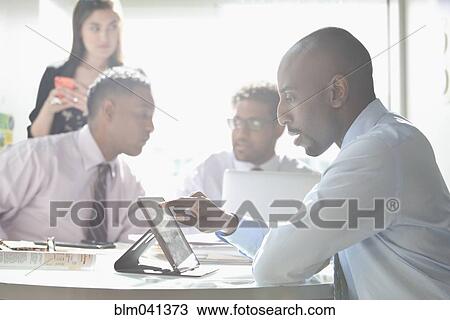 Businessman using digital tablet in office meeting View Large Photo Image Stock Image - Businessman using digital tablet in office meeting. Fotosearch