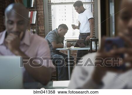 Stock Photo - Businessmen using laptop in office. Fotosearch