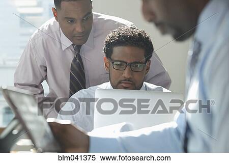 Stock Photography - Businessmen using technology in office. Fotosearch