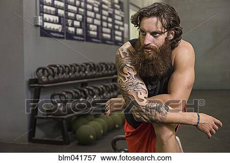 Stock Photo - Caucasian athlete kneeling in gym. Fotosearch