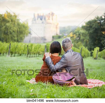 Stock Photograph - Caucasian couple enjoying picnic in vineyard. Fotosearch
