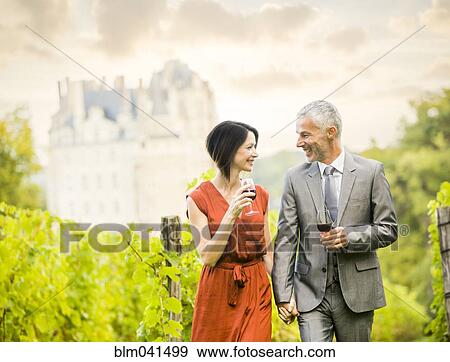 Stock Photo - Caucasian couple enjoying wine in vineyard. Fotosearch