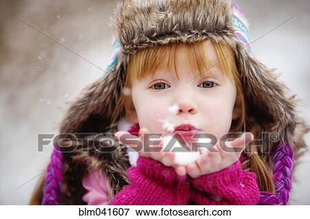 Stock Photo - Caucasian girl blowing handful of snow. Fotosearch