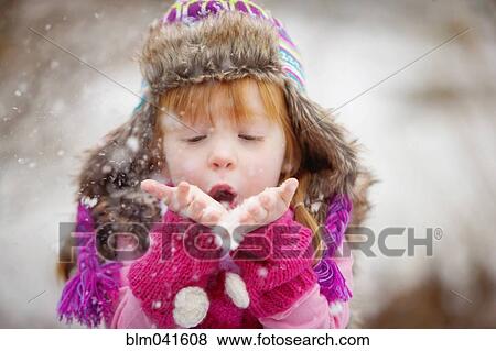 Stock Photo - Caucasian girl blowing handful of snow. Fotosearch